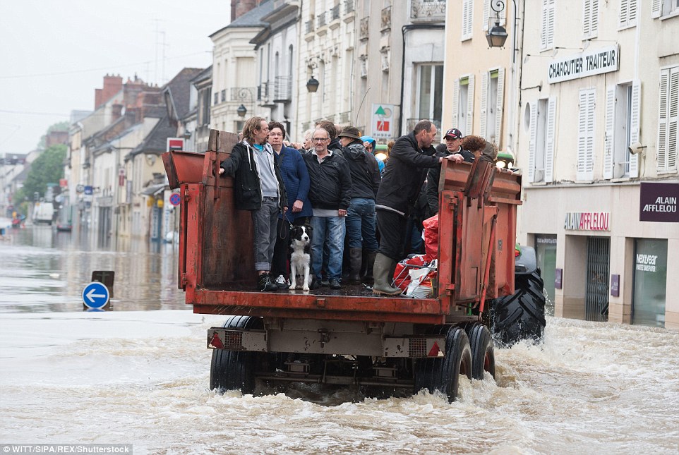 The rain-swollen River Seine in Paris reached its highest level in three decades Friday, spilling its banks. Residents are pictured being rescued in Nemours, Paris