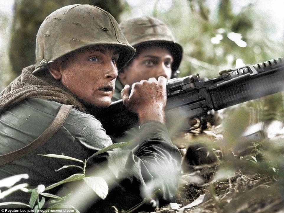 US machine gunner Specialist James R Pointer, left, of Cedartown, Georgia, and Private First Class Herald Spracklen of Effingham, Illinois, peer from the brush of an overgrown rubber plantation near the Special Forces camp at Bu Dop during a half hour firefight, Dec. 5, 1967. Their company-size patrol avoided an ambush when a patrol dog alerted the unit to the presence of enemy forces