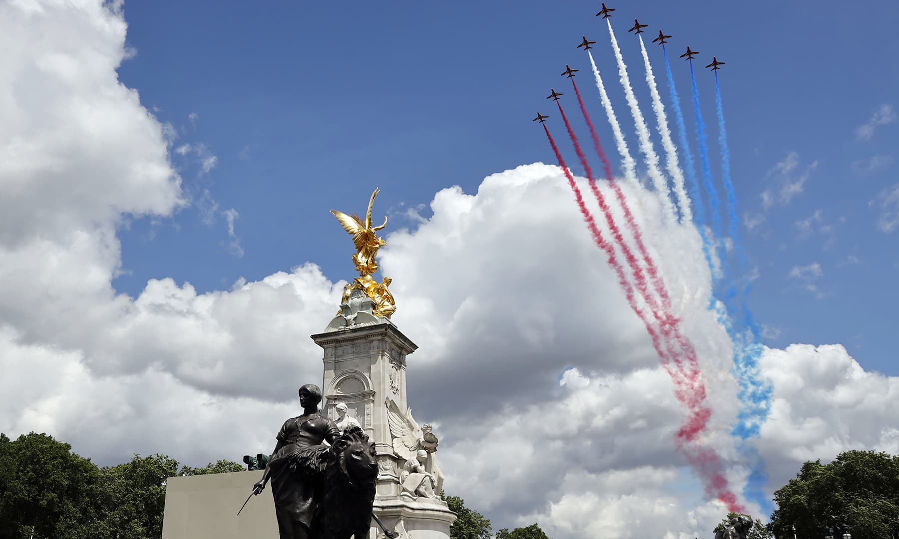 Britain's Red Arrows, the flying display team of the Royal Air Force (RAF) fly over The Queen Victoria Memorial outside Buckingham Palace, watched by members of the Royal Family on the balcony. — AFP