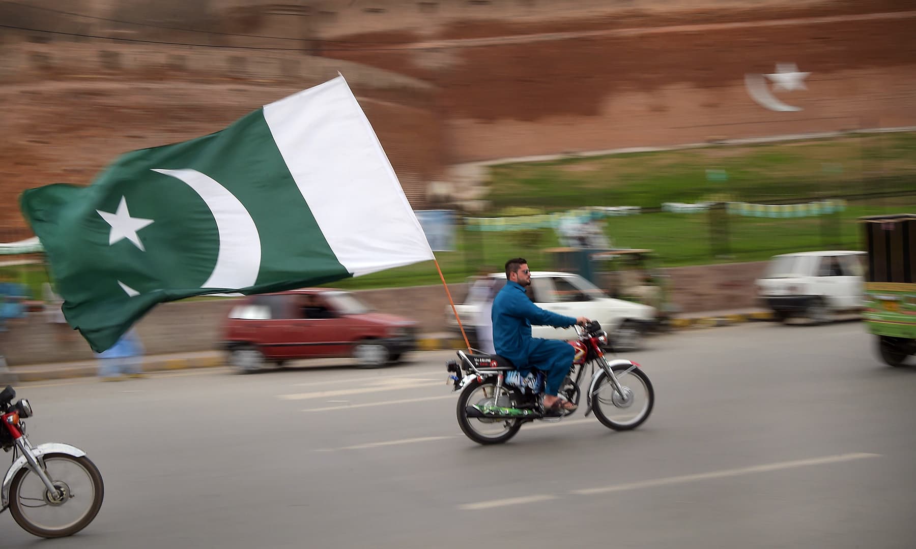 A man rides a motorbike with a national flag during Independence Day celebrations in Peshawar. — AFP