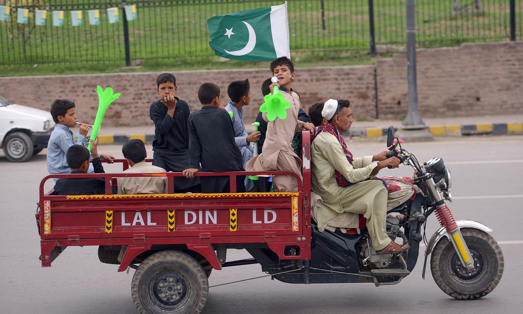 Youths gesture on a modified three-wheel vehicle during Independence Day celebrations in Peshawar. — AFP