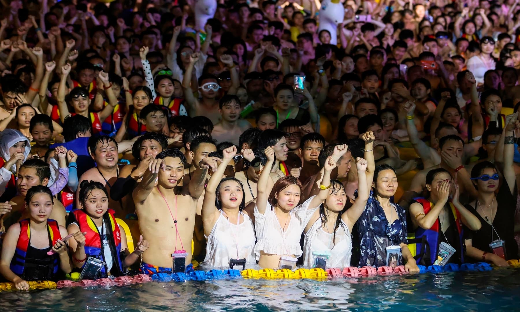 People watch a performance as they cool off in a swimming pool in Wuhan. — AFP