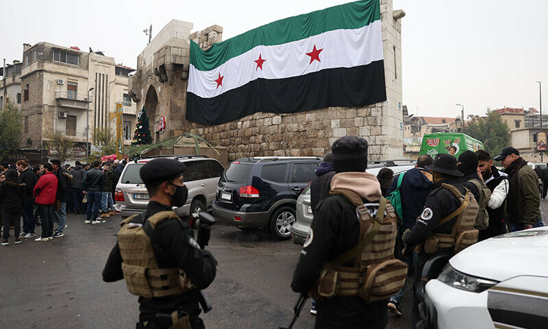 Syrian security forces, under the guidance of the transitional government, stand guard in a street in Damascus on December 24. — AFP