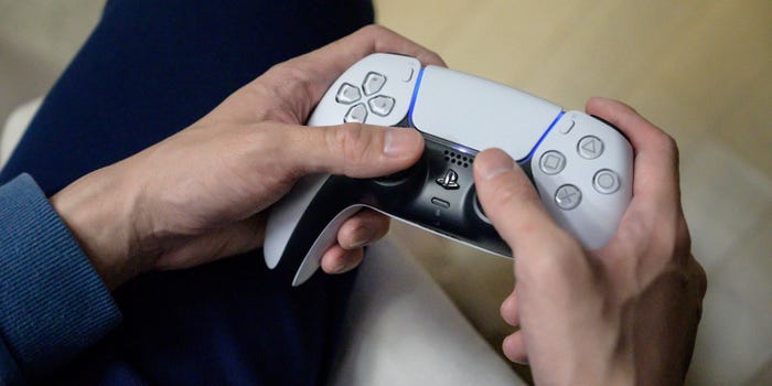 Person holding a PS5 DualSense controller.