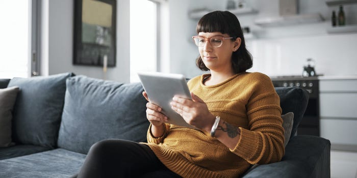 woman sitting on sofa in living room while using her tablet