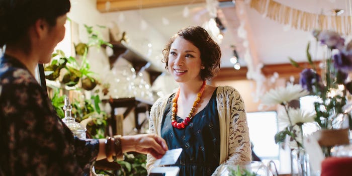 A woman uses a debit card to make a purchase at a shop.