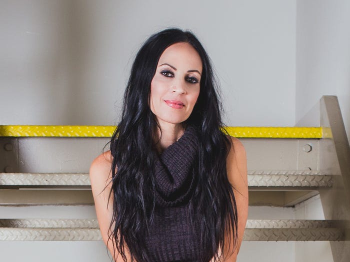 A woman with long dark hair sitting on stairs.