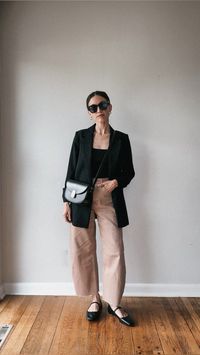 Casual chic spring outfit with a black tank, black blazer, tan barrel leg jeans, and black Mary Jane flats