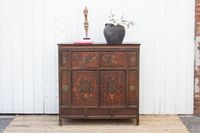 A vintage Mongolian buffet cabinet that exudes both beauty and functionality. This remarkable cabinet showcases a captivating painted scene on an aged red background, adding a touch of exotic allure to your space. Made from pine wood, this cabinet features a unique leather covering in the front, creating an interesting texture and visual contrast. The leather covering is adorned with a stunning phoenix flying design above royal medallions, symbolizing power and elegance. This Asian cabinet offer