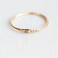 This delicate little diamond ring would make a great addition to any stacking ring set. This piece is simple and sweet, and can be customized in your choice of 14k gold metal color and finish. We ha