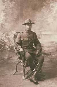 Unidentified African American soldier in uniform with marksmanship qualification badge and campaign hat, with cigarette holder in front of painted backdrop, 1917-1918.🇺🇸🙏 Bertin, Félix, photographer Library of Congress Prints and Photographs Division Washington, D.C. 20540 USA Retrieved from the Library of Congress, https://www.loc.gov/item/2017648678/.