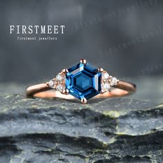 a blue and white diamond ring sitting on top of a piece of rock with the words firstmeet written below it