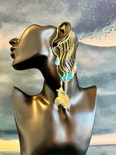 This enchanting water guardian ear cuff is sure to make a statement and bring out your inner magic! Gold ear cuff wrap is embellished with a light filigree gold fish charm and iridescent colorful glass drops dangling from wavy connectors and gold chains. This ear cuff is lightweight and perfect for adorning pierced and non-pierced Your jewelry is always wrapped in a jewelry bag and ready to be the perfect unique gift for yourself or someone you love! 💛 Fish Earrings Gold, Whimsical Brass Dangle Jewelry, Whimsical Gold Earrings For Festival, Festival Drop Earrings With Dangling Charms, Festival Jewelry Drop Earrings With Dangling Charms, Celestial Single Earring For Party, Festival Jewelry With Dangling Drop Earrings, Gold Pierced Ear Cuff For Festival, Unique Adjustable Gold Clip-on Earrings