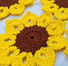 yellow and brown crocheted flowers are arranged on a white tablecloth with dark brown centers