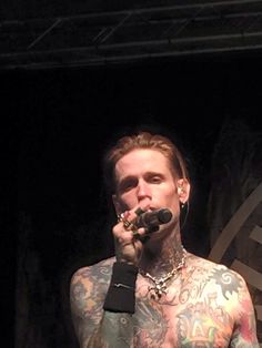 a man with tattoos on his chest holding a microphone