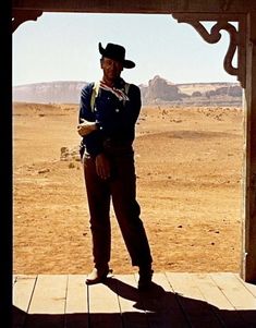 a man wearing a cowboy hat standing on a porch