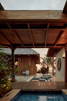 an outdoor swimming pool surrounded by plants and wooden structures with blue tiles on the floor