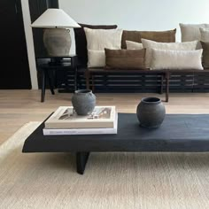 a coffee table with two vases sitting on top of it next to a couch