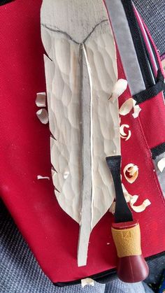 a red piece of luggage with a white feather on it and a black pipe sticking out of it