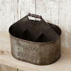 an old metal bucket with the words country living on it sitting on a wooden bench