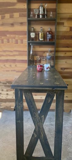 a wooden table sitting in front of a shelf filled with bottles