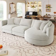 a living room with a large sectional couch in the center and lots of furniture around it