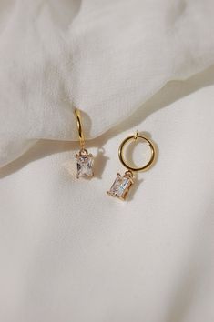 These dainty earrings are made with glass rhinestone charms and 18 karat gold plated huggie hoops. This gold plating protects against wear and tear, tarnishing, and light contact with substances such as water. All earrings are handcrafted with care and custom made to meet your unique needs. Closure options: * Pierced gold hoops are hypoallergenic and nickel free (18 karat gold plated). * Clip on gold hoops are hypoallergenic and nickel free (18 karat gold plated). How to wear clip ons: Hold the earring in one hand while pulling the closure open with the other hand, place the earring onto the thin upper earlobe, then slide the earring down the earlobe to secure in place. Please feel free to message me for any questions! Dainty Dangle Earrings, Clip On Hoop Earrings, Earrings Crystal, Earrings Dainty, Dainty Earrings, Earrings Photo, Gold Hoops, Etsy Fashion, Huggies Earrings