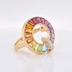 Introducing our breathtaking 18K Gold Rainbow Gemstones Diamond Circle Ring—a true masterpiece that celebrates vibrant hues and timeless elegance. Crafted from luxurious 18-karat gold, this ring is a stunning embodiment of color and sophistication, designed for those who appreciate the finer things in life. Formal Multicolor Brilliant Cut Rings, Luxury Multicolor Rings With Center Stone, Elegant Multicolor Gemstones With Center Stone, Fine Jewelry Multicolor Diamond Ring With Center Stone, Elegant Multicolor Sapphire Ring With Cubic Zirconia, Elegant Multicolor Round Cut Rings, Elegant Multicolor Brilliant Cut Rings, Multicolor Brilliant Cut Ring, Multicolor Luxury Diamond Ring As A Gift