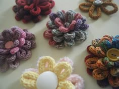 several crocheted flowers are arranged on a table with a button in the center