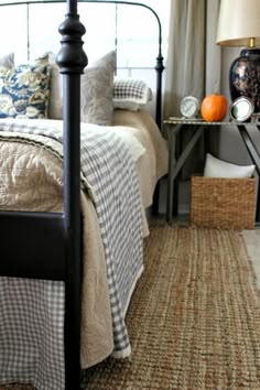 a bed room with a neatly made bed next to a night stand and a basket