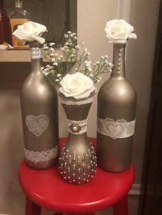 three silver vases with white flowers in them