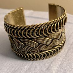 a close up of a gold bracelet on a white table cloth with a light background