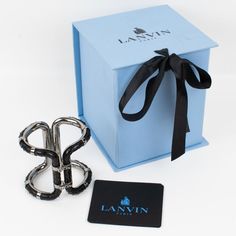 A sophisticated Lanvin Paris modernist clamper bracelet.  This statement piece features an oversized gray steel framing in a futuristic design ornate with black python leather skin. The bracelet is engraved inside: "Lanvin Paris - Made in Italy." The two locking clasps are working perfectly. We will deliver the bracelet with its original branded gift box and label. Measurements: inside across is 2.25 in wide x 1.75 in deep (5.7 x 4.5 cm) - width is 2.75 in (7 cm) - inner circumference is 6.69 in Luxury Rectangular Cuff Bracelet For Formal Occasions, Modern Evening Cuff Bracelet, Luxury Metal Evening Cuff Bracelet, Luxury Black Cuff Bracelet, Designer Black Cuff Bracelet For Gift, Designer Black Cuff Bracelet As Gift, Designer Black Cuff Bracelet For Formal Occasions, Modern Silver Cuff Bracelet For Evening, Luxury Black Metal Cuff Bracelet