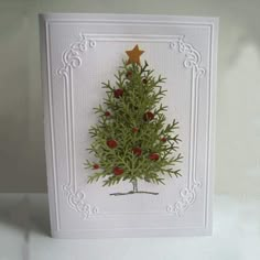 a card with a christmas tree on the front and red berries on the back, sitting on a white surface