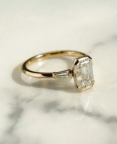 an engagement ring with a single stone in the center on a marble countertop top