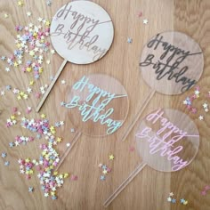 three happy birthday cake toppers with confetti and sparkles on the table