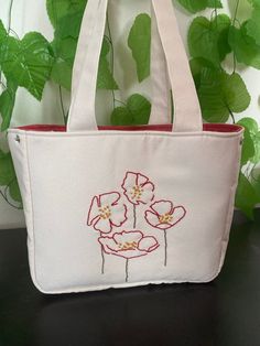 This bag combines natural beauty with handcrafted elegance! Adorned with meticulously hand-embroidered floral patterns on durable Natural Linen, this bag is unique and special in every detail. Measuring 28 cm x 23 cm x 11 cm, this bag offers both stylish and practical options for daily use. ✨ Features: Spacious Interior: The bag features three different compartments; a zippered pocket, a regular pocket, and a bottle pocket to easily organize your belongings. Easy Use: The magnetic snap closures allow for easy opening and closing. Comfortable Strap: The 6 cm strap ensures comfortable carrying. Natural Linen: Made from durable Natural Linen, adorned with handcrafted floral embroidery. This bag is not just an accessory but also a companion that reflects your style and appreciation for craftsm Floral Embroidered Canvas Tote Bag For Everyday Use, White Rectangular Bag With Machine Embroidery, White Rectangular Bags With Machine Embroidery, Rectangular Canvas Bag With Floral Embroidery For Daily Use, Beige Embroidered Top Handle Bags, Everyday Floral Embroidery Tote Shoulder Bag, Everyday Tote Shoulder Bag With Floral Embroidery, Everyday Floral Embroidered Tote Shoulder Bag, White Floral Embroidered Tote Shoulder Bag