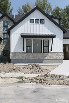 a large white house with black trim and windows on the front door is under construction