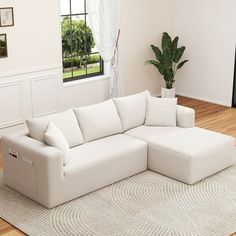 a white couch sitting on top of a wooden floor next to a potted plant