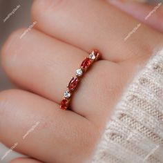 a woman's hand holding an orange and white diamond ring