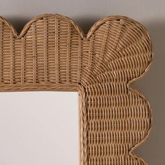 a wicker frame with a white square mirror on the wall next to it,