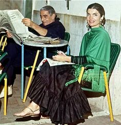 two people are sitting at tables and one is reading a newspaper while the other sits on a chair