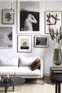 a living room filled with white furniture and pictures on the wall above it's coffee table