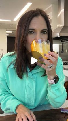 a woman sitting at a table drinking orange juice