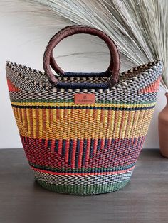 a basket sitting on top of a wooden table next to a vase and grass plant