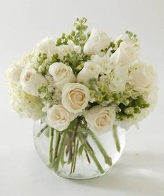 a vase filled with white flowers and greenery