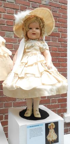 a small doll is sitting on top of a white box in front of a brick wall