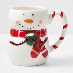 a snowman mug with a candy cane in its mouth