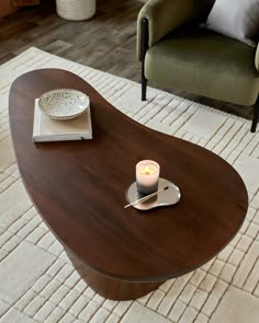 a coffee table with a candle on it in a living room next to a chair