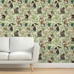 a white couch sitting in front of a wallpaper with cats and birds on it